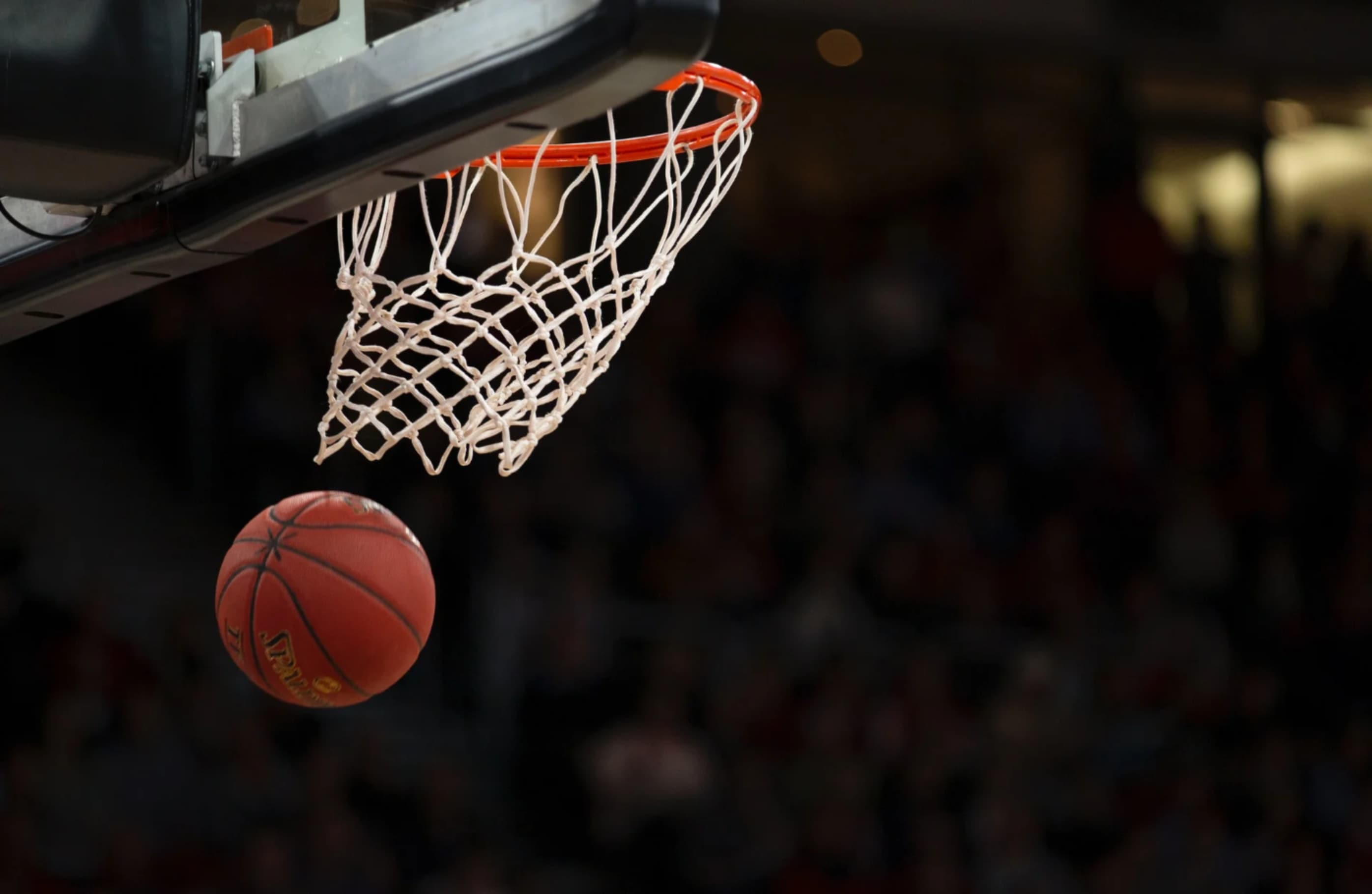 Basketball going through hoop net on indoor court
